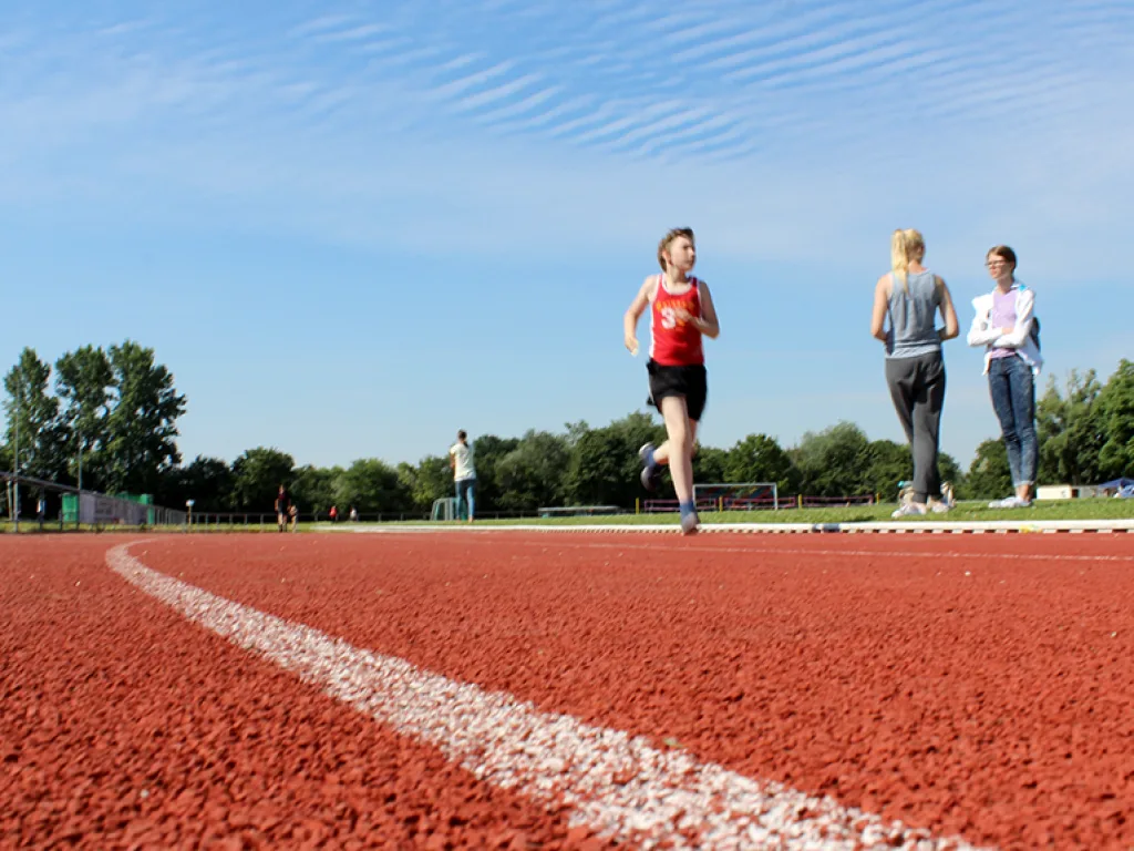 Läuferinnen auf der Bahn vor blauem Himmel.